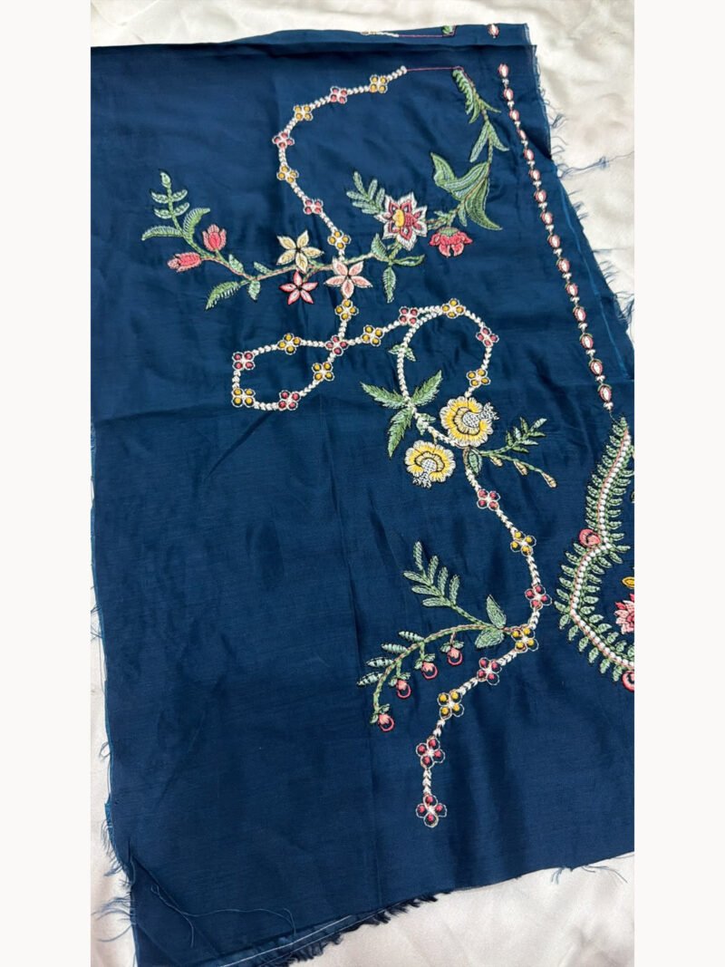 Blue viscose shirt fabric with pink and yellow floral embroidery and green leaves – close-up