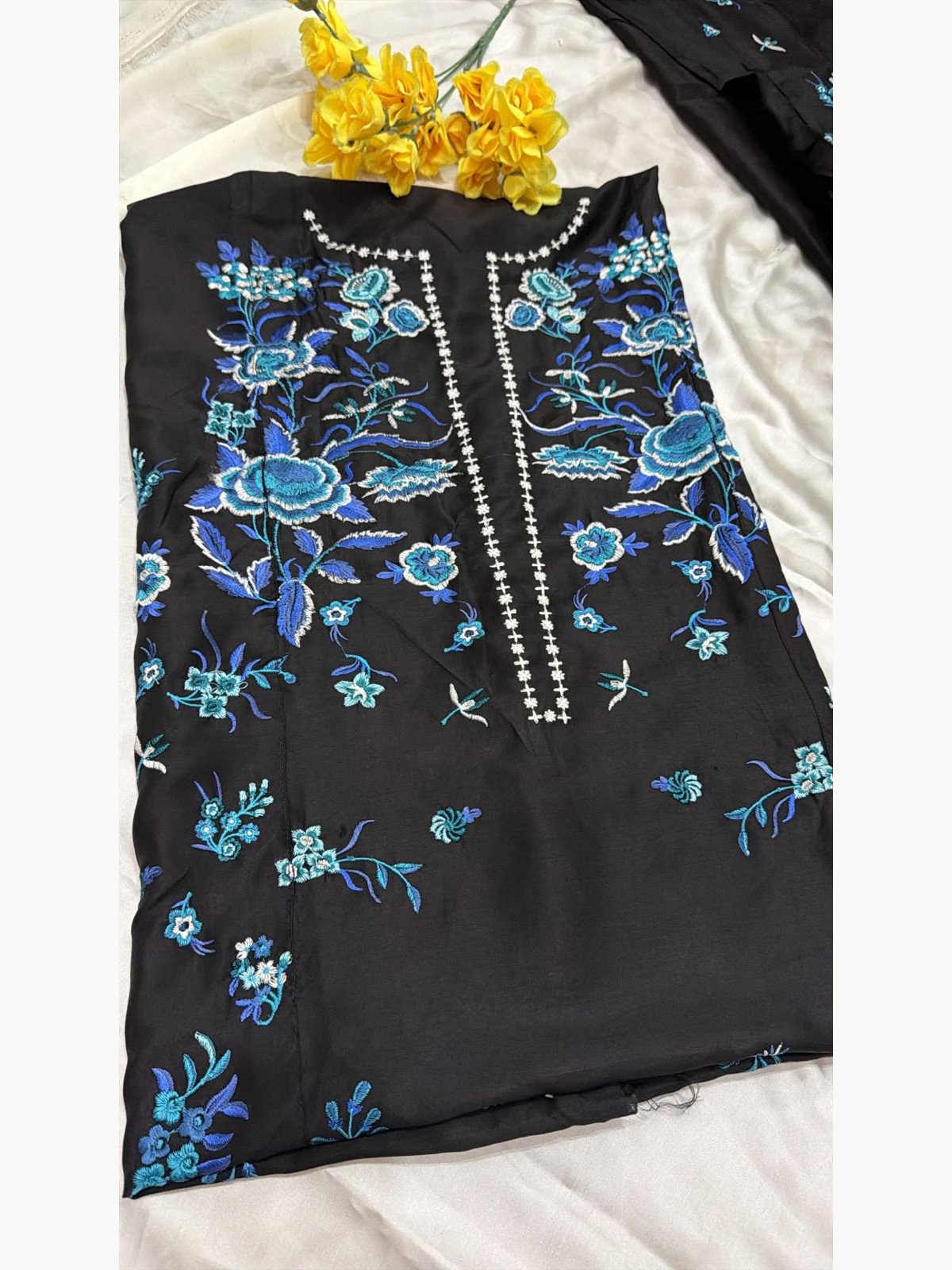 Black viscose shirt front with blue floral embroidery and detailed neckline – close-up